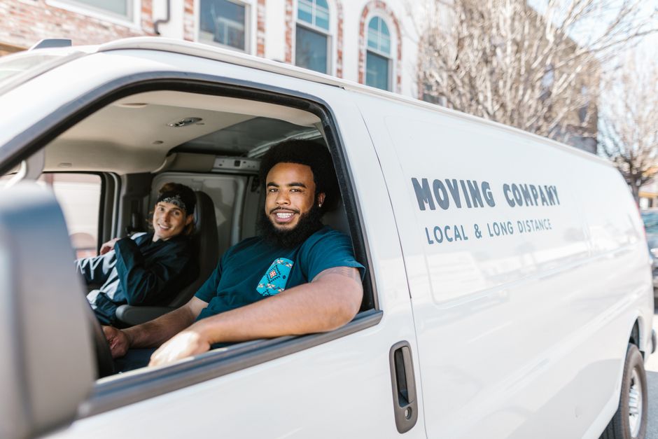 Friendly professional movers smiling and carrying boxes